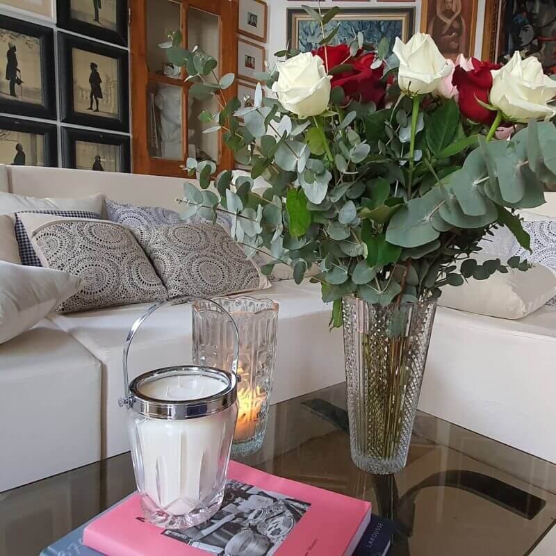Bougie de la marque Jeudi Bougies, posée sur une table basse, a côté d'un gros bouquet de fleurs
