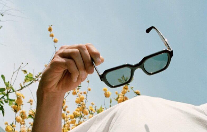 photo ensoleillée, un homme tient une paire de lunettes jimmy fairly