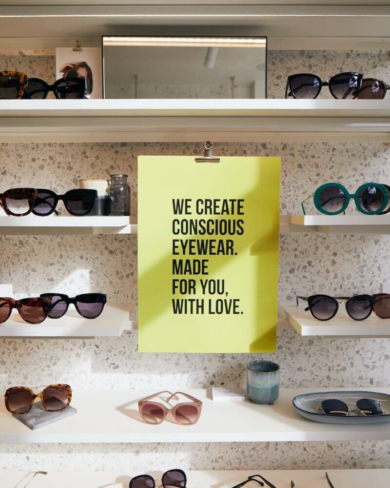 Etagères d'une boutique Jimmy Fairly sur laquelle sont exposées des lunettes et une citation sur les valeurs de la marque