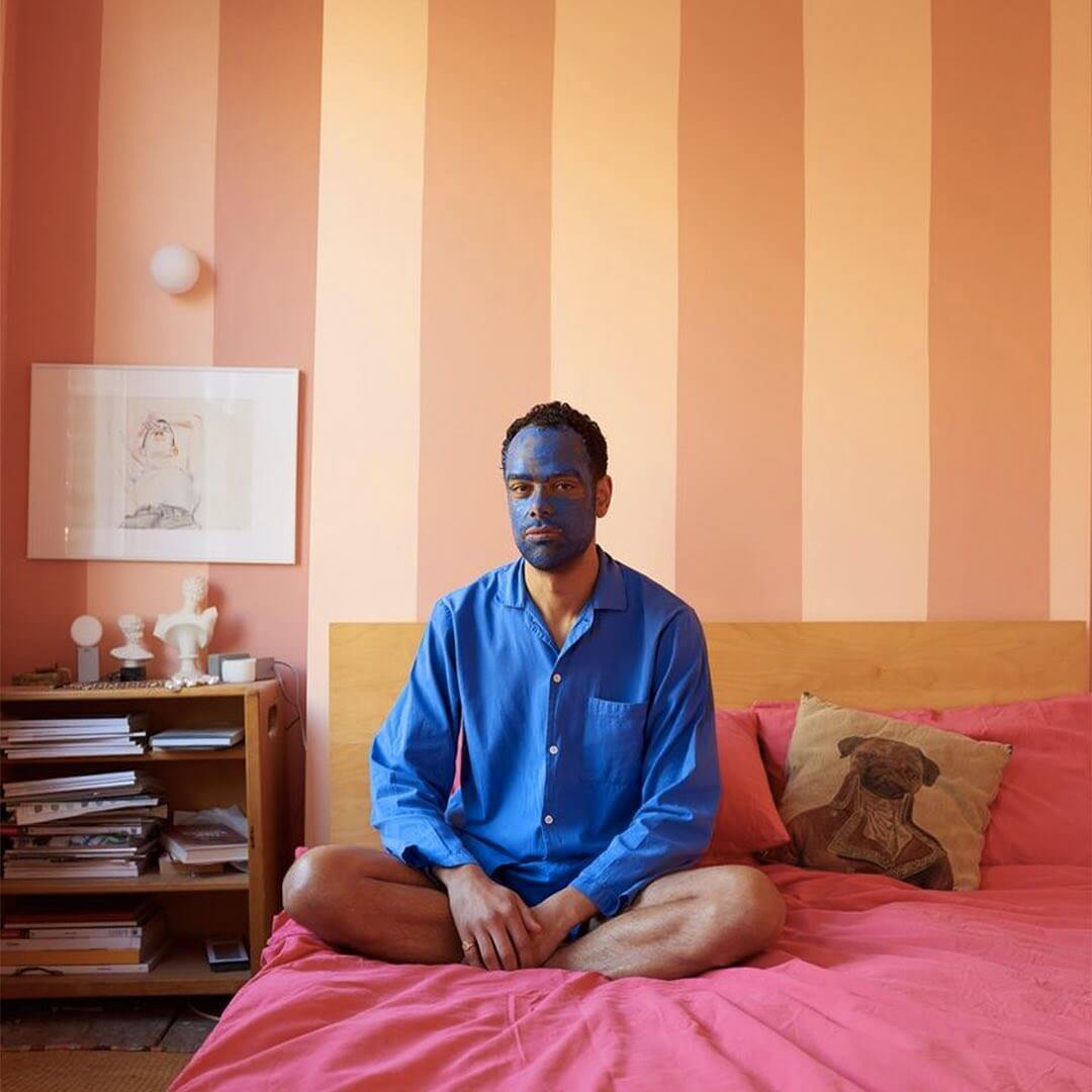 Homme assis sur un lit avec un masque de soin Horace sur le visage