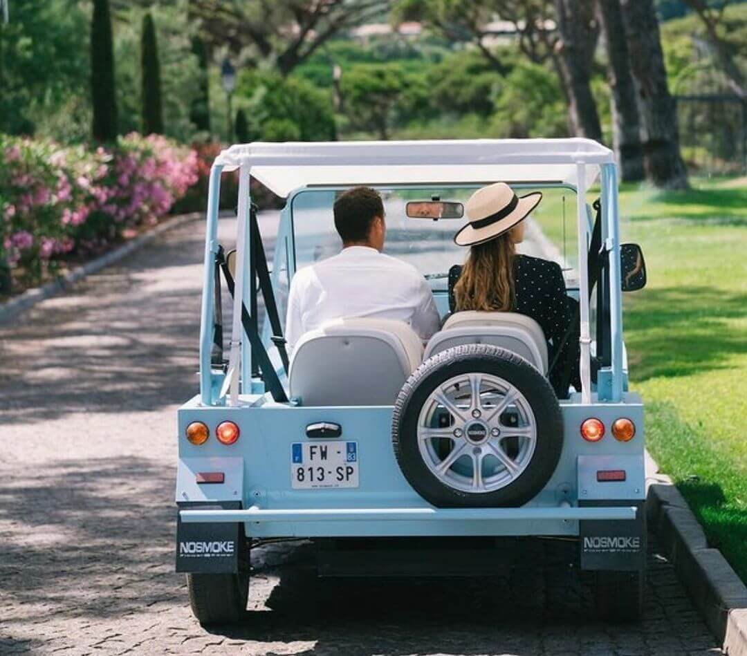 Photo d'un couple de dos, se promenant en mini moke