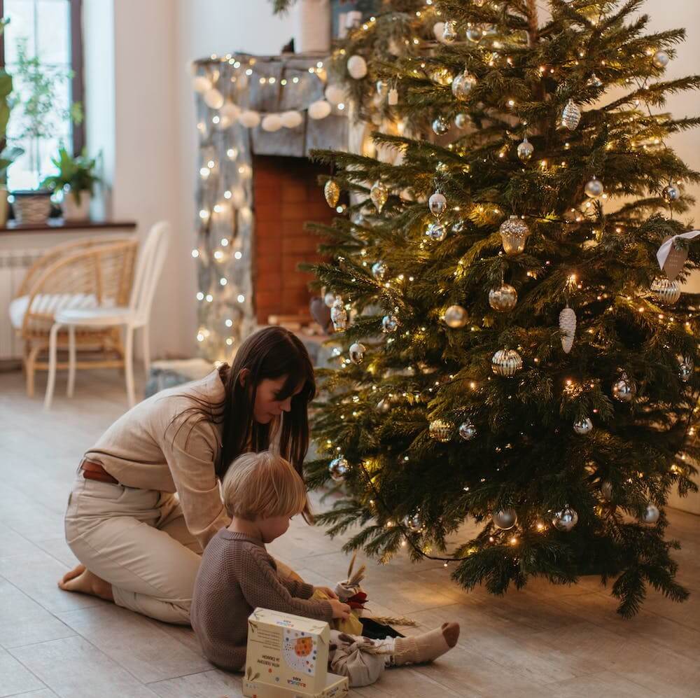 Une mère et son jeune enfant devant le sapin